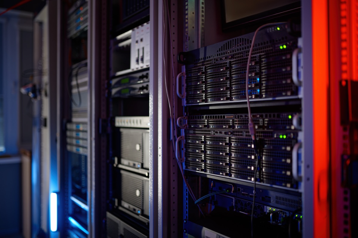 Server racks in a dim server room with blue and green indicator lights and a cabinet edge glowing red