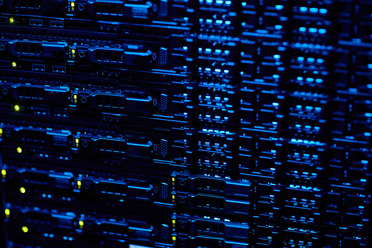 A dark, close-up view of server hardware in a data centre rack, lit by rows of blue and green status indicators